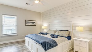 Ein Schlafzimmer mit Bett, Nachttischen, Deckenventilator und Fenster.