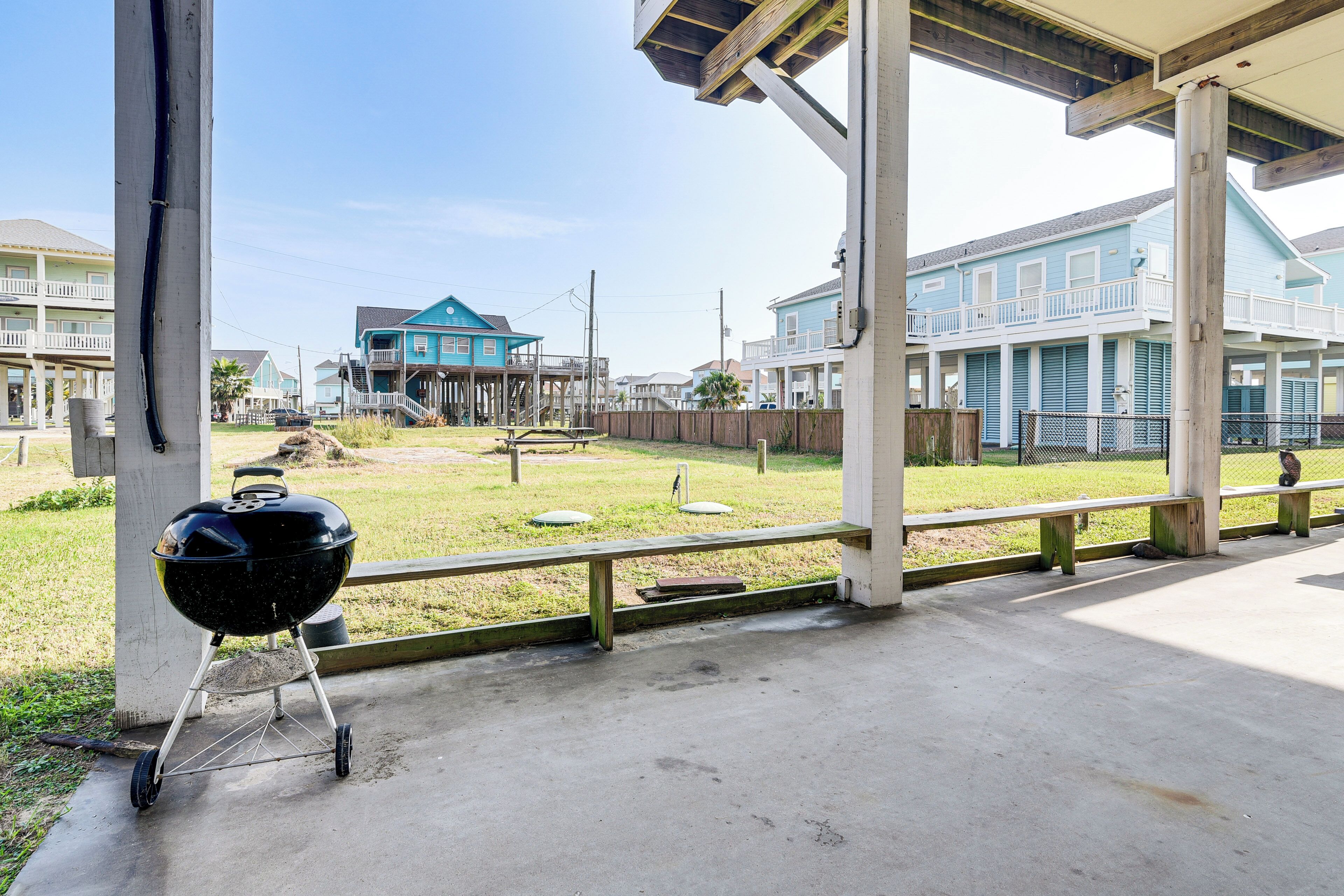 Un espacio al aire libre cubierto con una parrilla, una terraza de madera y vistas a casas al fondo.