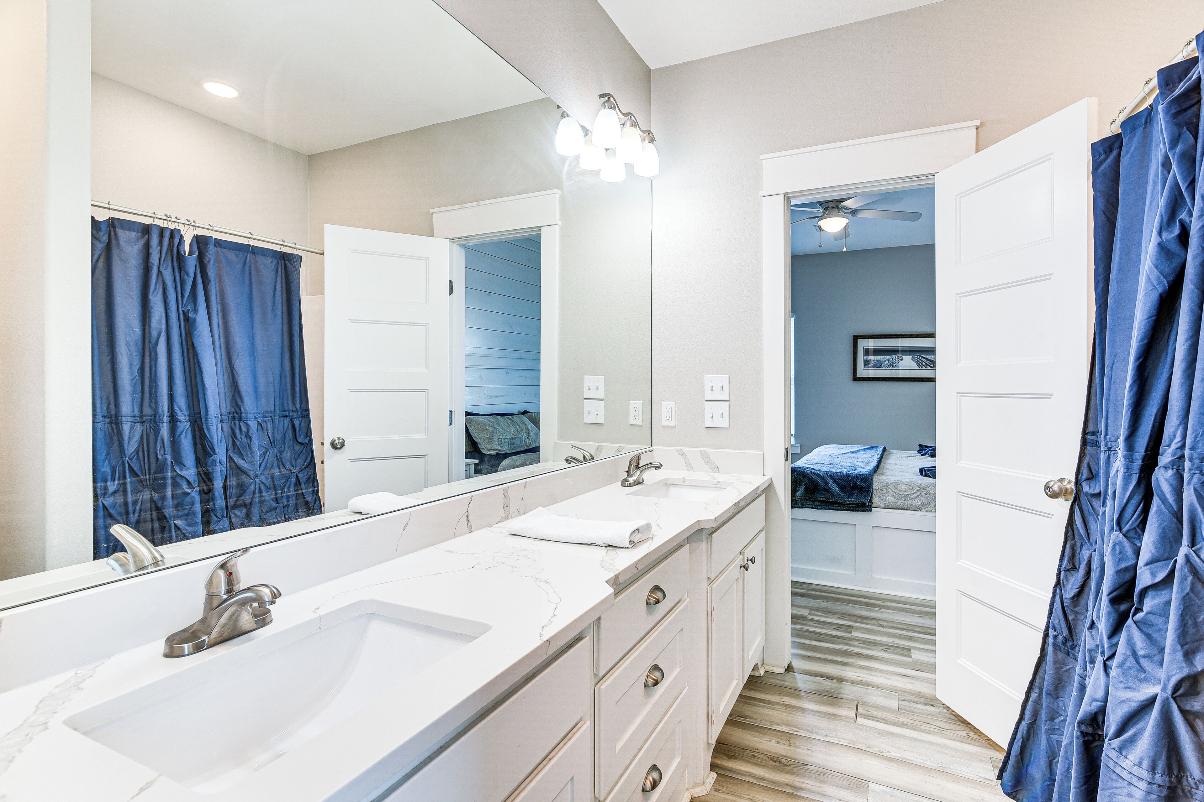A bathroom with two sinks, a large mirror, and a shower curtain.