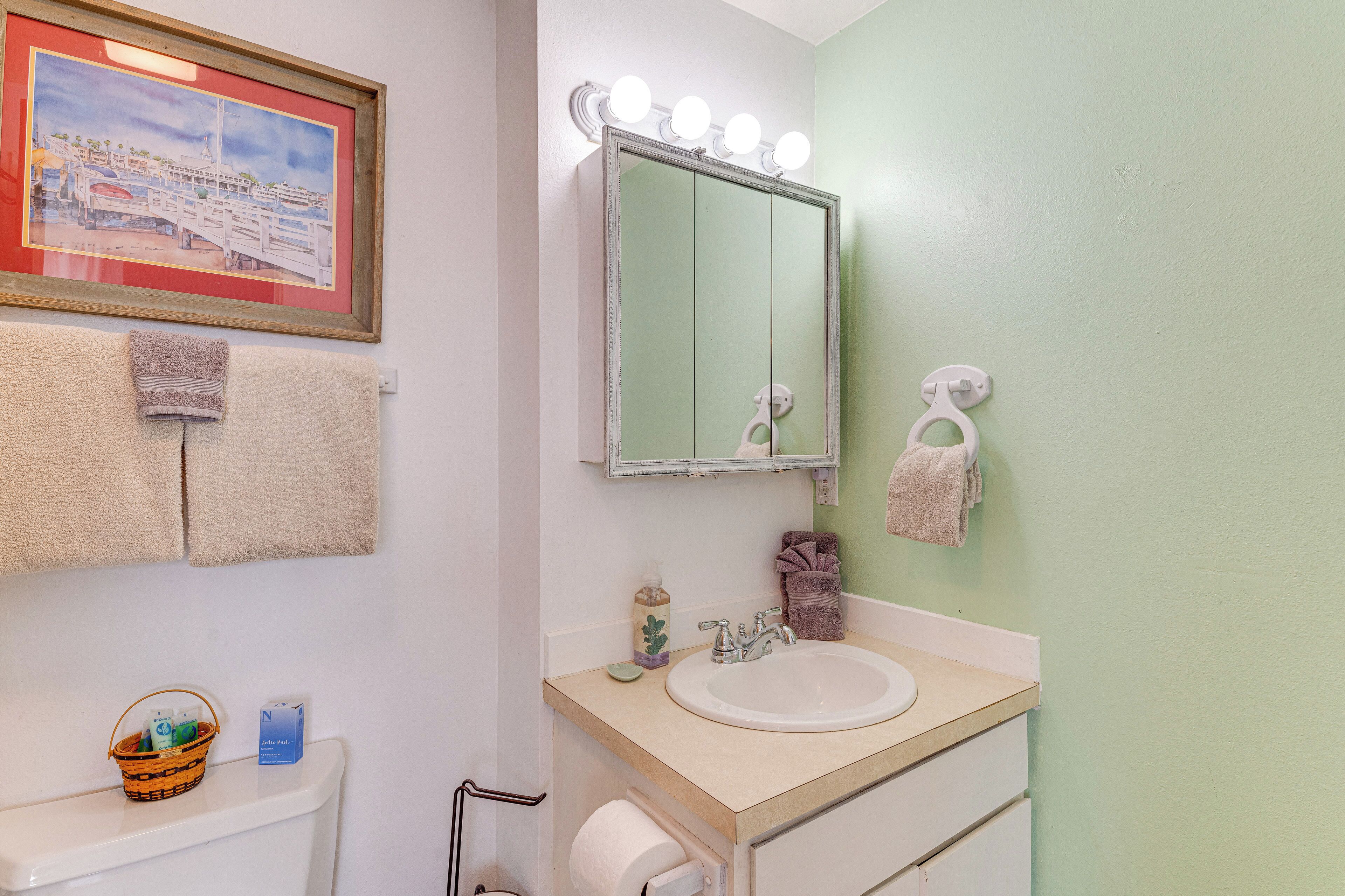 Un baño con lavamanos, espejo y perchero para toallas.