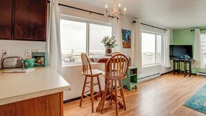 A kitchen with wooden chairs, a dining table, a chandelier, and a view through large windows.