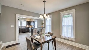 A dining area with a wooden table and chairs, a chandelier, and a view of the kitchen and living area. - Lakeside Garden Home - 1 Mile to Main Street! (Fort Wayne)