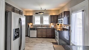 A modern kitchen with stainless steel appliances, wooden cabinets, and a large window. - Lakeside Garden Home - 1 Mile to Main Street! (Fort Wayne)