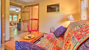 A cozy living room with a colorful sofa, a wooden coffee table, and a red chair. - Rustic-yet-cozy Cabin w/ Patio, 12 Mi to Asheville (Arden)