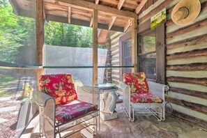 A log cabin with two wicker chairs with floral upholstery and a small table. - Rustic-yet-cozy Cabin w/ Patio, 12 Mi to Asheville (Arden)