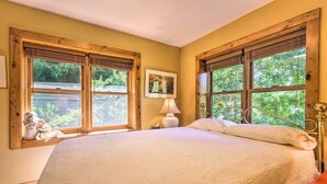 A bedroom with a large bed, wooden window frames, and a view of greenery outside. - Rustic-yet-cozy Cabin w/ Patio, 12 Mi to Asheville (Arden)