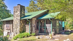 A rustic log cabin with a stone chimney, a green metal roof, and a screened porch. - Rustic-yet-cozy Cabin w/ Patio, 12 Mi to Asheville (Arden)