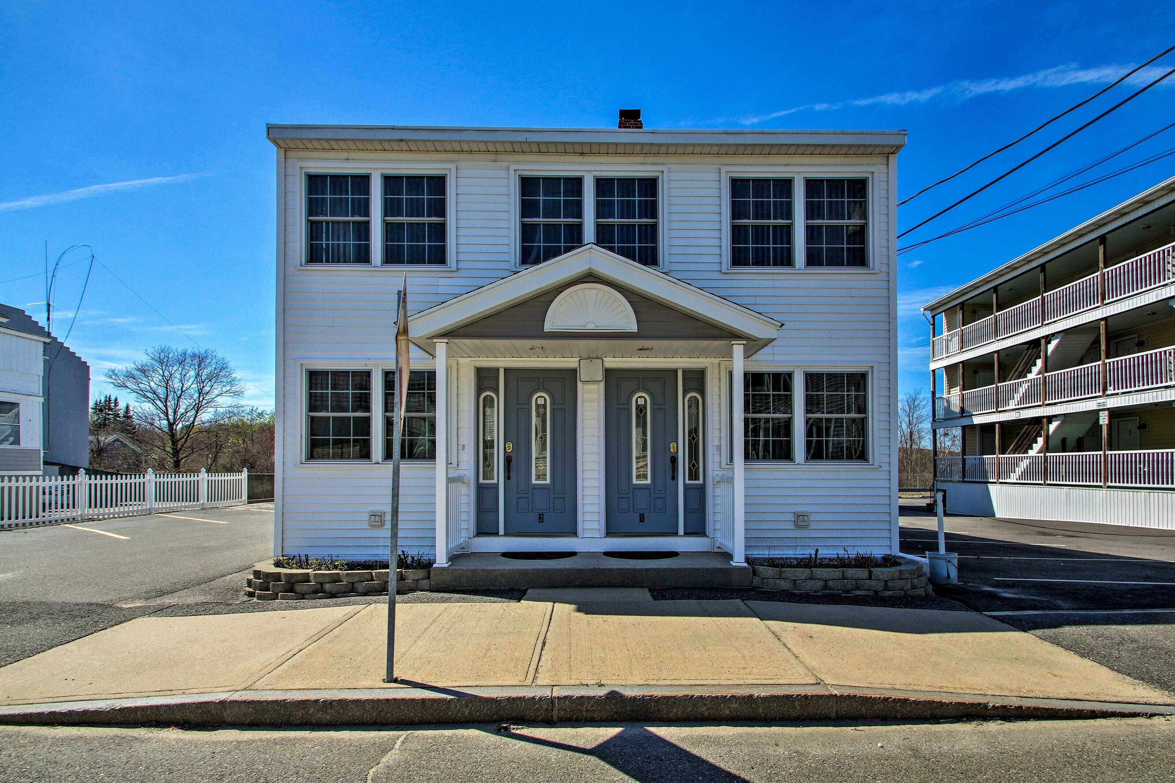 A two-story white building with a symmetrical facade, a central entrance with a fanlight, and a small porch area.