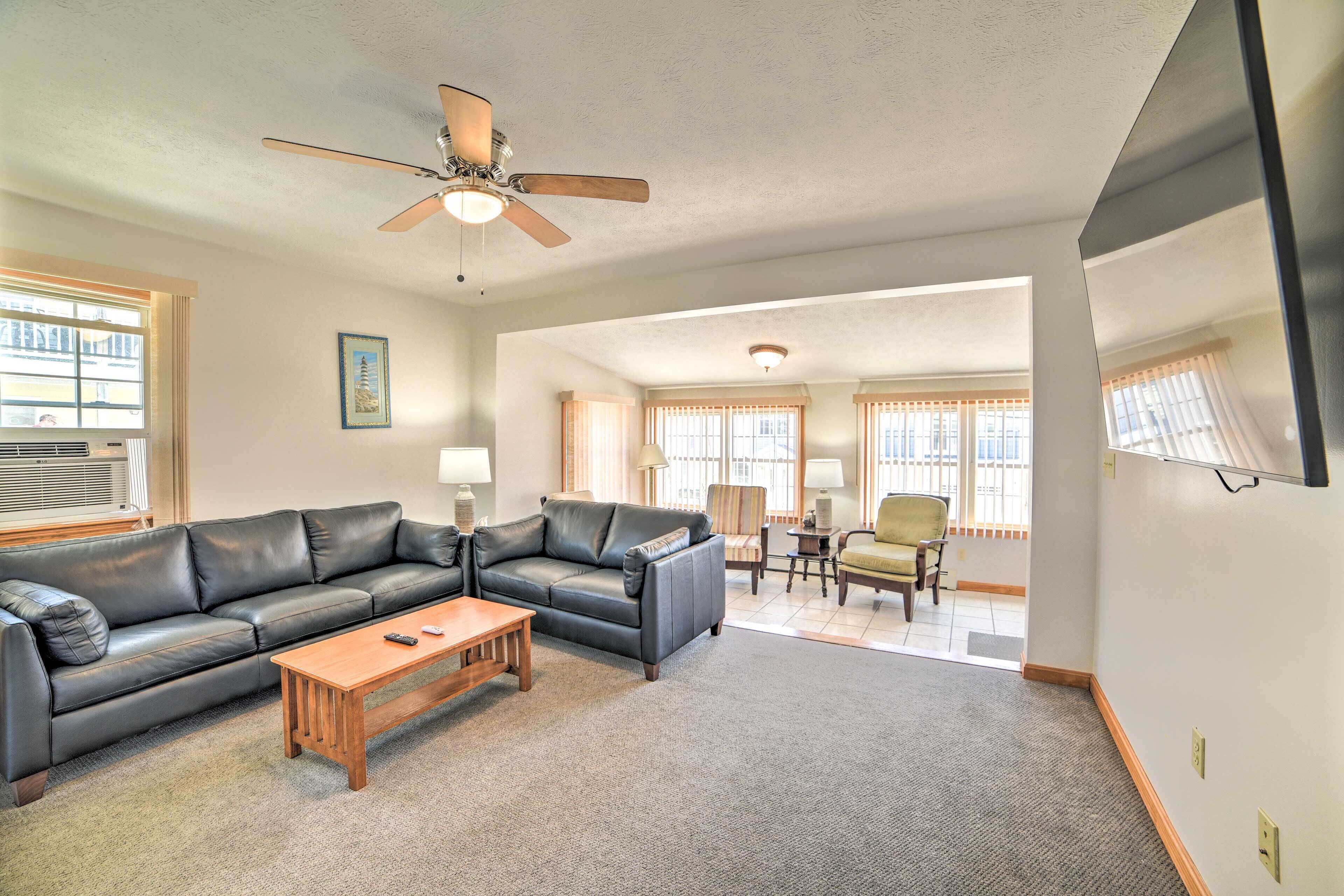 A living room with a black leather sofa, wooden coffee table, and a ceiling fan.
