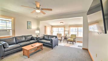 A living room with a black leather sofa, wooden coffee table, and a ceiling fan.