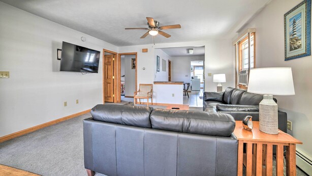 A living room with a gray sofa, a wooden side table with a lamp, and a ceiling fan. - Old Orchard Beach Apt - Walk to Beach & Pier! (Old Orchard Beach)