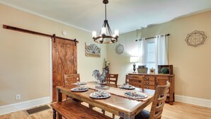Comedor con mesa de madera dispuesta para cuatro personas, una araña y decoración rústica.