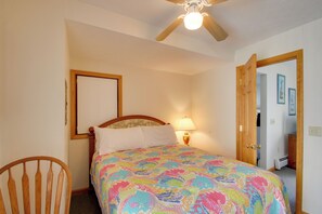 A bedroom with a bed, a chair, a ceiling fan, and a door leading to another room. - Apt in Old Orchard Beach - Walk to Bay + Pier (Old Orchard Beach)