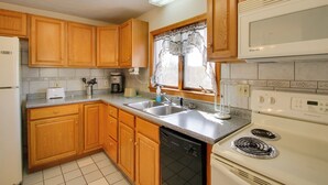 A kitchen with wooden cabinets, a white stove, a microwave, and a window with a curtain. - Apt in Old Orchard Beach - Walk to Bay + Pier (Old Orchard Beach)