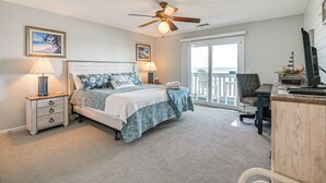 A bedroom with a bed, bedside lamps, a ceiling fan, a desk, and a view of the outdoors. - Oceanfront Condo w/ Pool Access in Surfside Beach! (Surfside Beach)