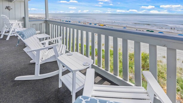 A covered balcony with white furniture, offering a view of the beach and ocean. - Oceanfront Condo w/ Pool Access in Surfside Beach! (Surfside Beach)