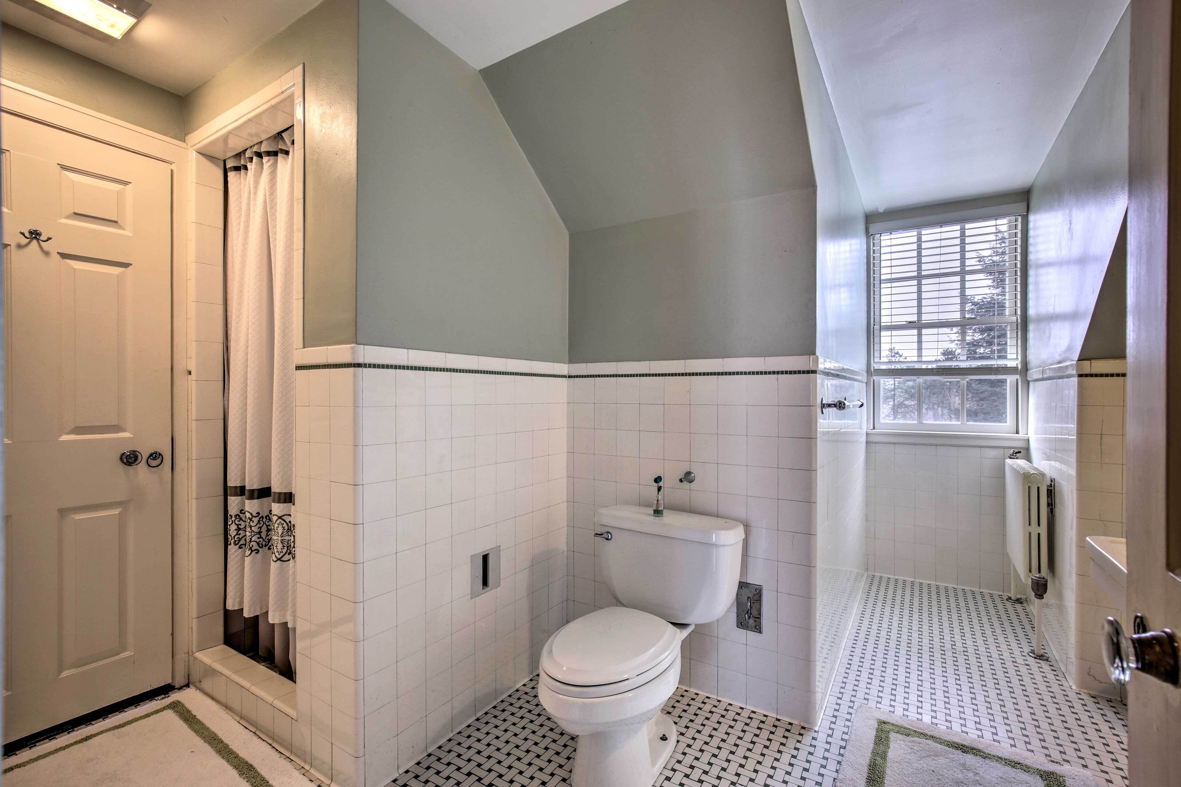 A bathroom with a toilet, a shower, and a window.