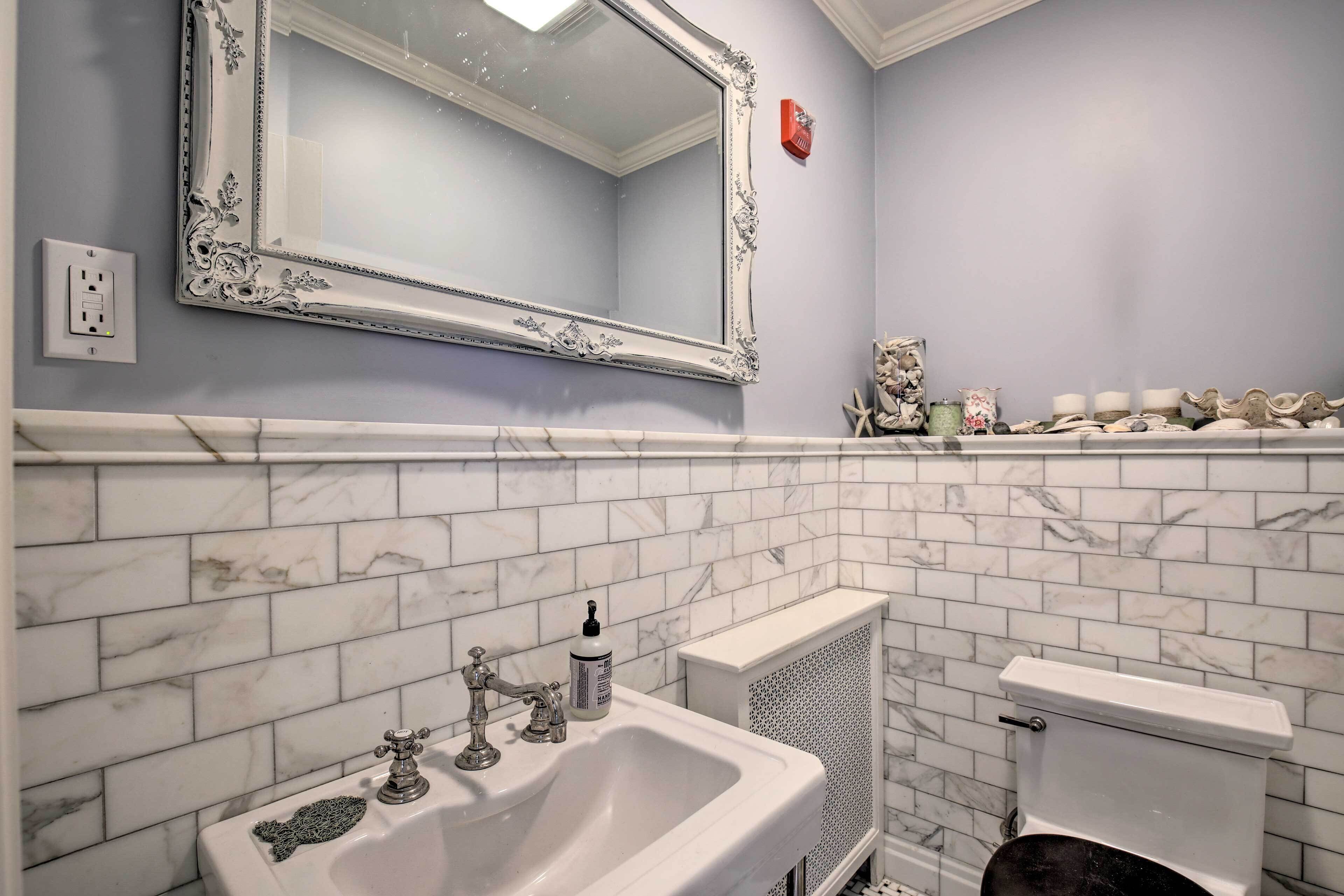Un baño con un lavabo blanco, un espejo grande con un marco ornamentado y un inodoro con tanque blanco.