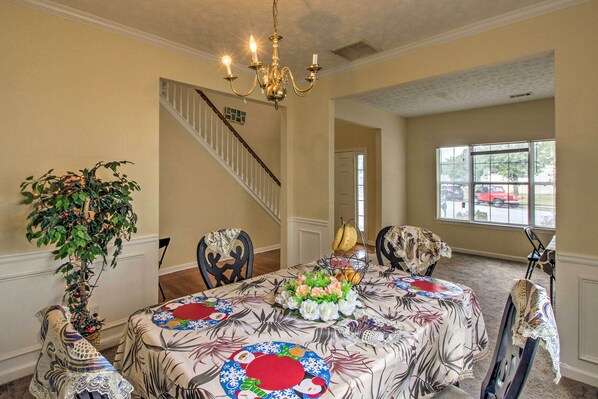 A dining area with a chandelier, a staircase, and a view of the outside. - Spacious Stone Mountain Home - Walk Everywhere! (Stone Mountain)
