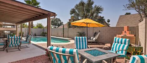 A backyard with a pool, outdoor seating, and a pergola.