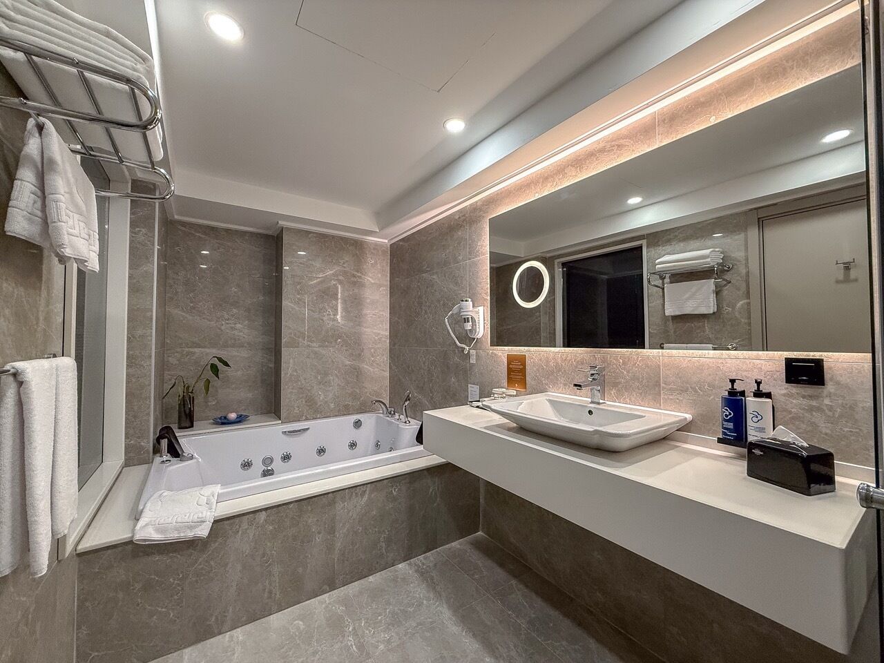 Une salle de bain moderne avec une baignoire, un lavabo et un grand miroir.