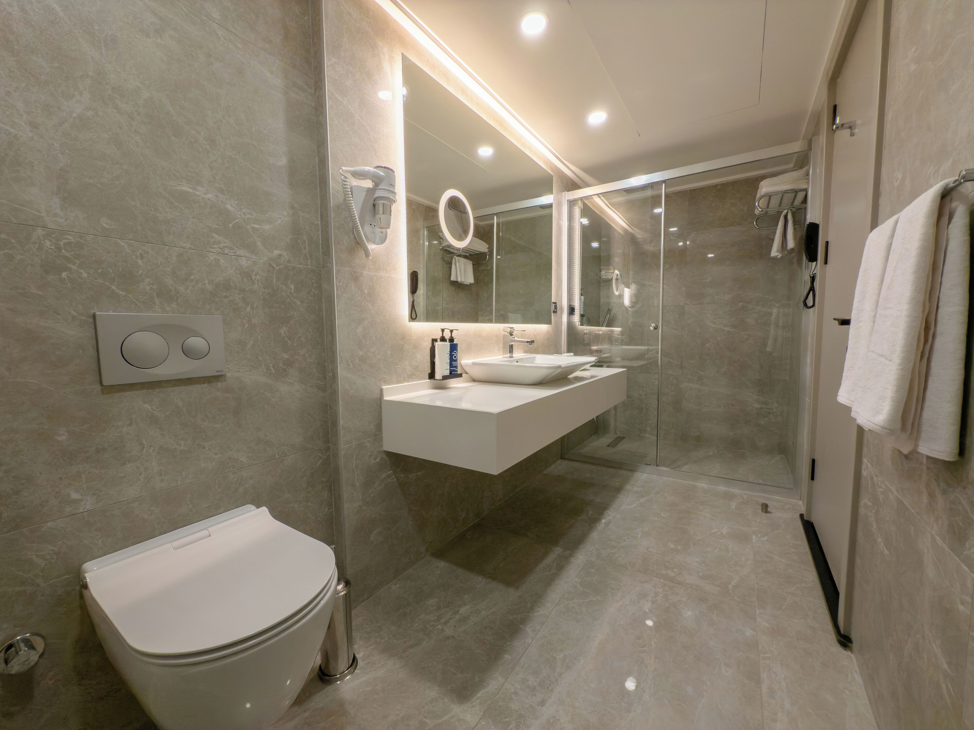 A modern bathroom with a toilet, a sink with a mirror, and a shower area.