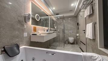 A modern bathroom with a large bathtub, a glass-enclosed shower, a vanity with a mirror, and a towel rack.