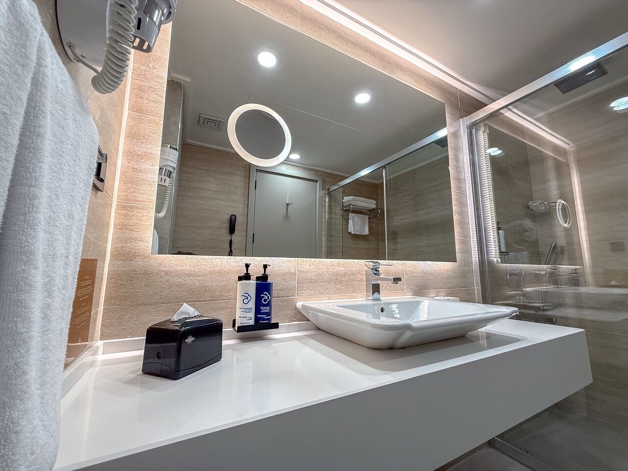 Een moderne badkamer met een wit wastafelmeubel, een spiegel en een douchecabine van glas.