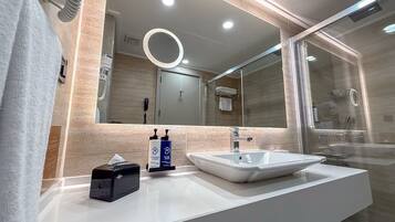 Een moderne badkamer met een wit wastafelmeubel, een spiegel en een douchecabine van glas.