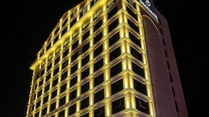 Un hotel de varios pisos con fachada moderna, ventanas iluminadas y un llamativo cartel de marca.