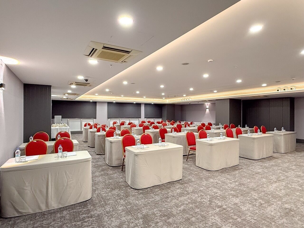 A conference room with multiple tables and chairs, arranged in rows.