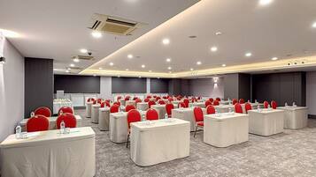 A conference room with multiple tables and chairs, arranged in rows.