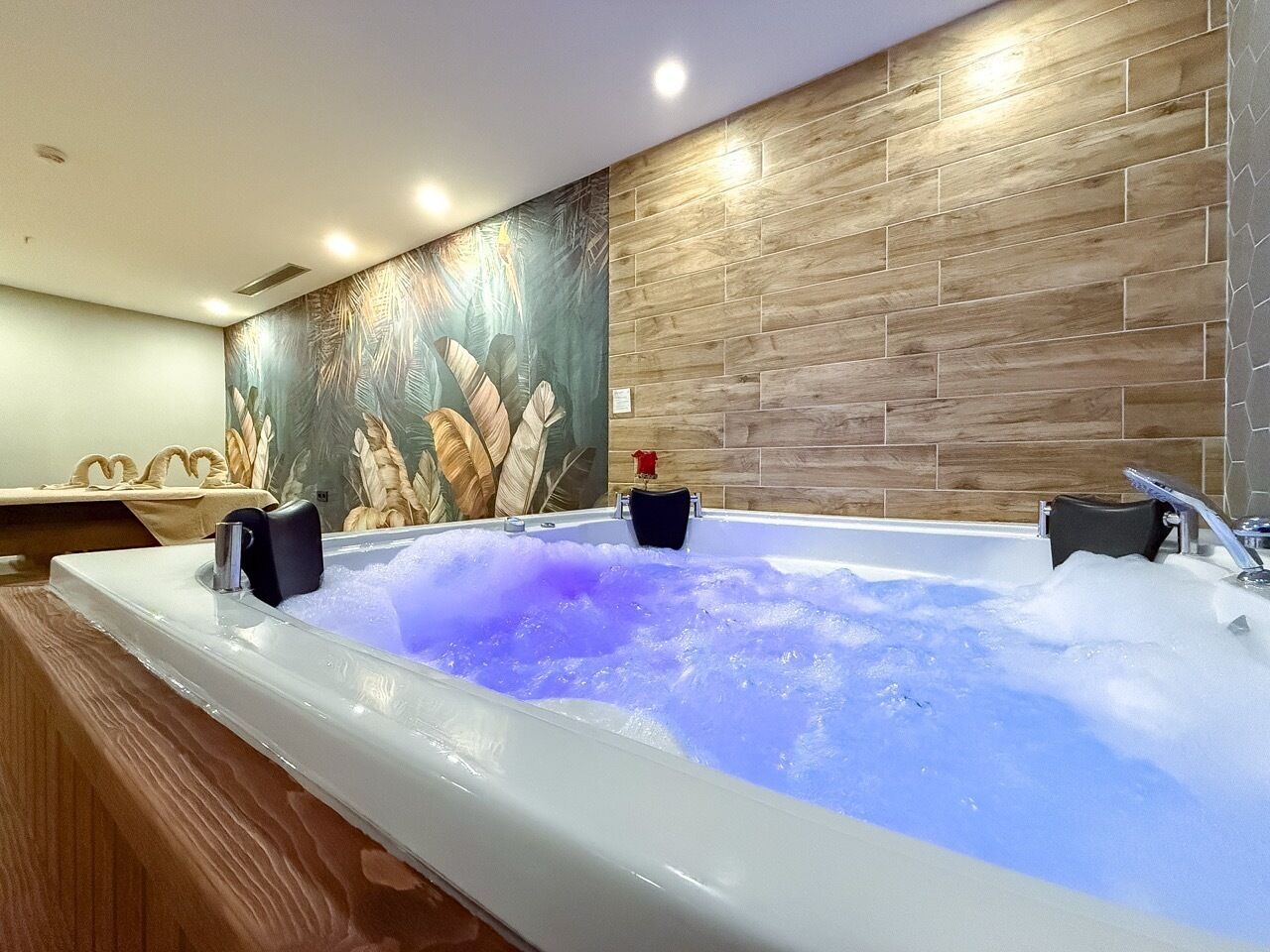 A spa area with a large hot tub, wooden wall panels, and a decorative mural.