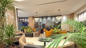 Un vestíbulo moderno con zonas de estar, plantas y vistas del interior.
