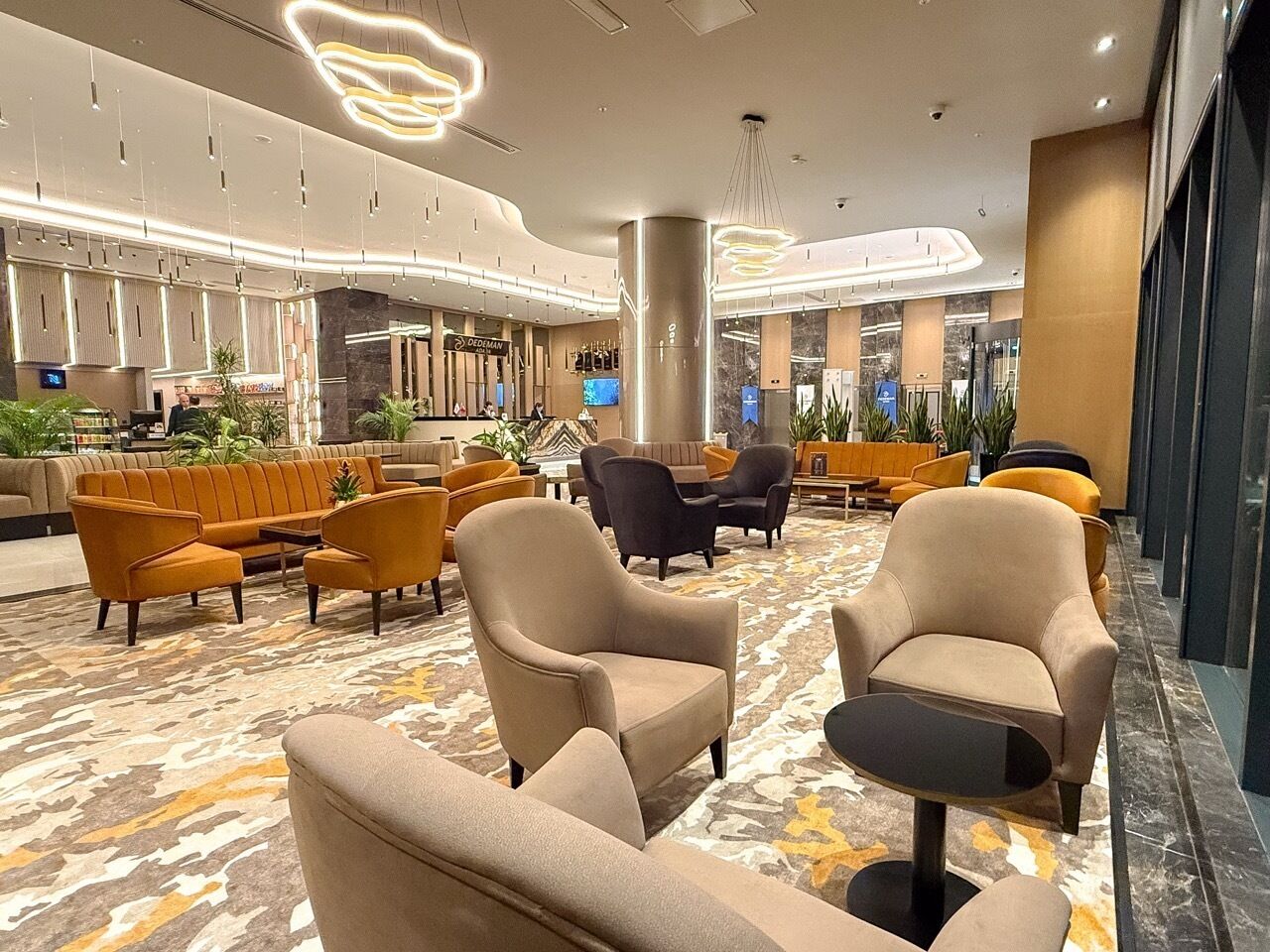 A spacious lobby with multiple seating areas, including sofas and armchairs, and a central pillar.