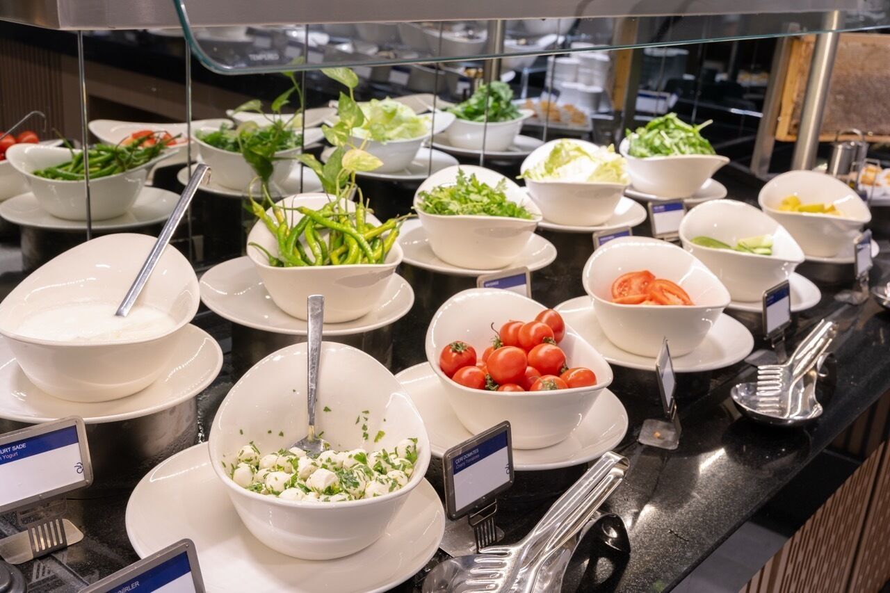 Un bufé con diversos platos, como ensaladas, verduras y un parfait de yogur.