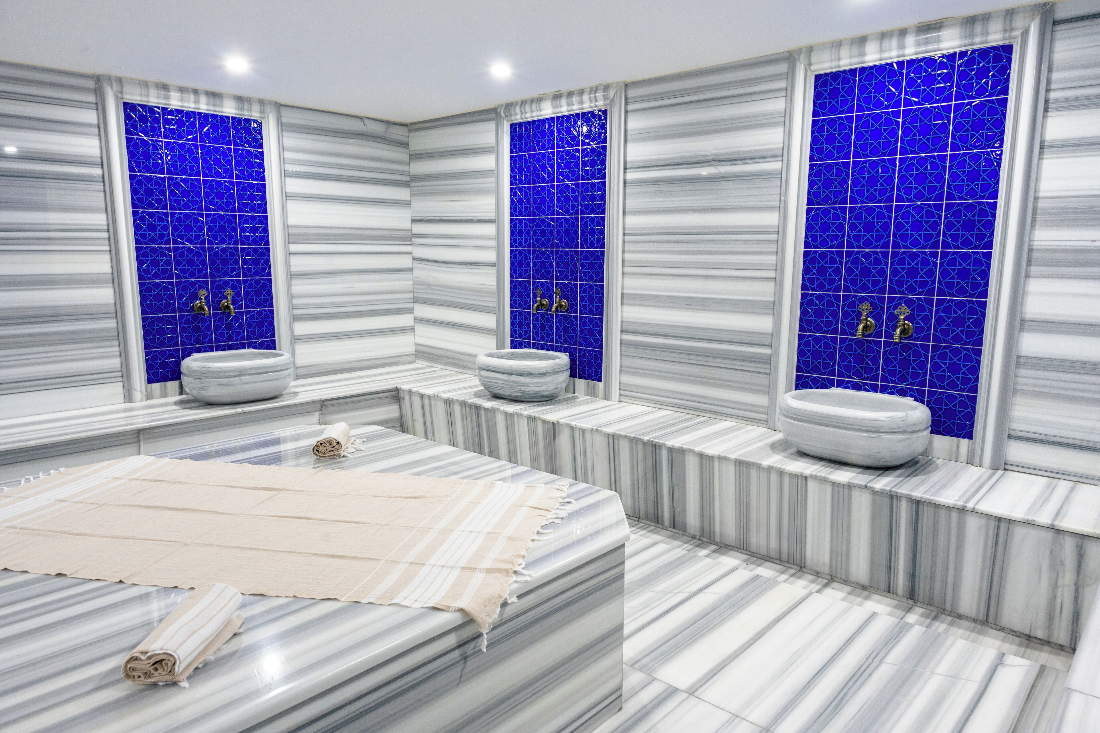 A modern bathroom with a large marble vanity, two sinks, and a blue-tiled wall.
