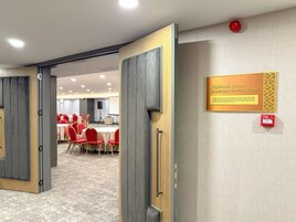 Una sala de reuniones con una puerta de madera, un letrero que la identifica como sala de reuniones y un botón rojo de emergencia en la pared.