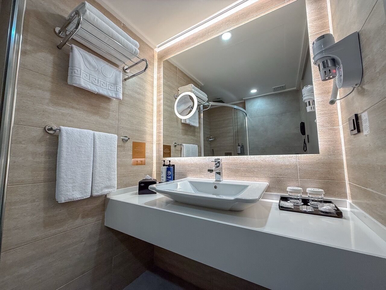 Un bany modern amb un lavabo gran, un mirall i penjalls per a tovalloles.
