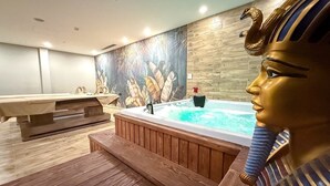 Un área de spa con un jacuzzi, terraza de madera y un mural en la pared.