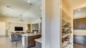 A modern kitchen with a central island, bar stools, a flat-screen TV, and built-in cabinets. - Mtn Views, Pool & Hot Tub: Phoenix Oasis (Phoenix)