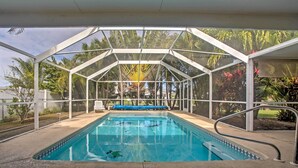 A covered swimming pool with a clear view of palm trees and a blue sky. - Tropical Cape Coral Home w/ Private Dock on Canal! (Cape Coral)