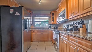 A kitchen with wooden cabinets, a stainless steel refrigerator, a microwave, and a stove. - Tropical Cape Coral Home w/ Private Dock on Canal! (Cape Coral)