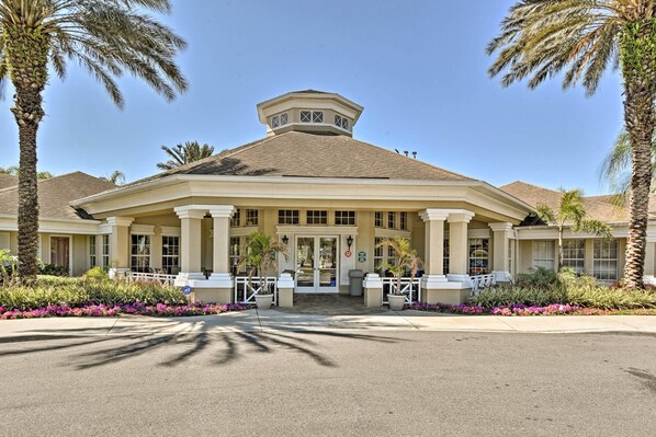 A hotel with a central entrance, palm trees, and a covered patio area.