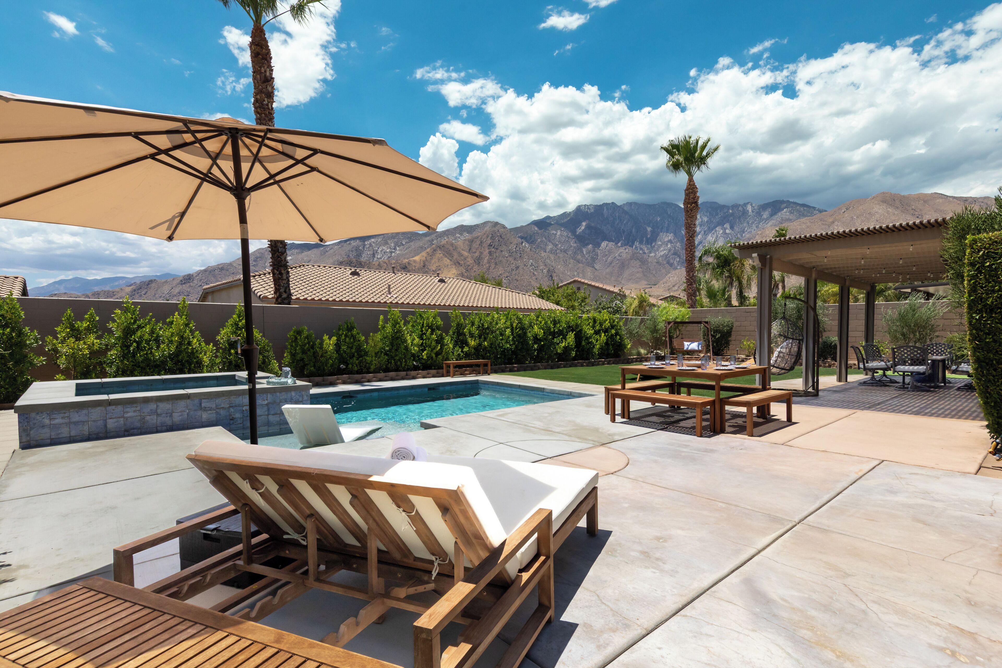 Un espace aménagé au bord de la piscine, avec des chaises longues, une table et un parasol.
