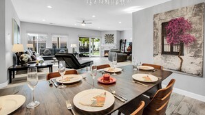A dining area with a long table set for a meal, a chandelier, and a large painting of a tree on the wall. - Near Downtown: Palm Springs Home w/ Mountain Views (Palm Springs)