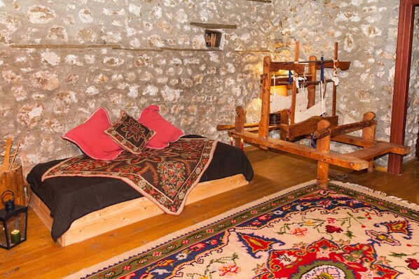 A rustic room with a wooden bed, a traditional loom, and a patterned rug.