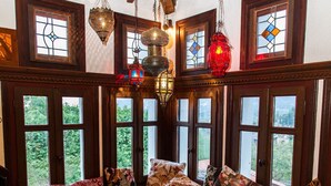 Una stanza accogliente con una panca in legno, cuscini decorati e un tavolino tradizionale con oggetti ornamentali.
