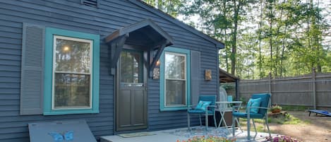 A blue house with a porch, two chairs, and a table.