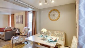 A dining area with a table set for two, a sofa, and a decorative wall piece.